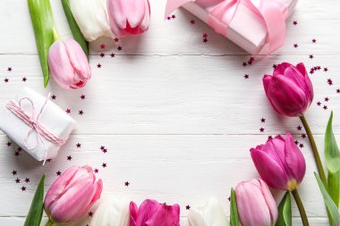 Frame made of beautiful tulip flowers and gift boxes on light wooden background, closeup