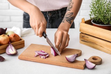 Woman cutting fresh onion in kitchen
