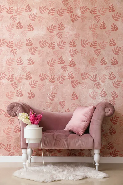 Stylish sofa and beautiful hyacinth flowers near pink wall in room