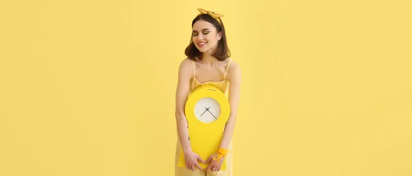 Stylish young woman with clock on yellow background. Banner for design