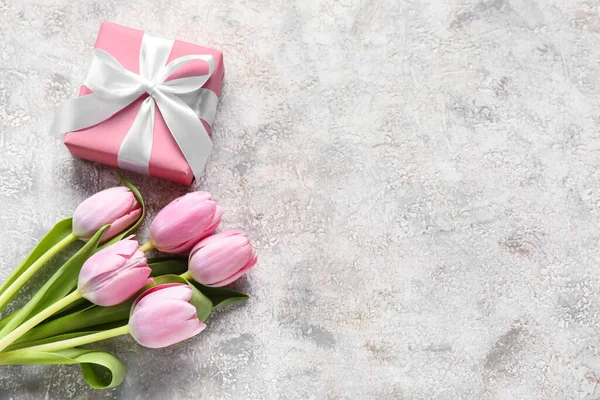 Beautiful tulip flowers and gift box on light background