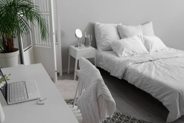 Workplace with laptop and earphones in light bedroom