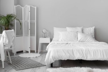 Interior of white bedroom with folding screen and palm tree