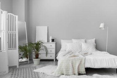 Interior of white bedroom with drawers and palm tree