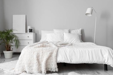 Interior of white bedroom with drawers and palm tree
