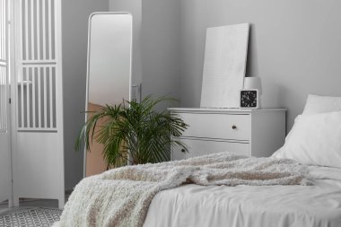 Interior of white bedroom with folding screen and mirror