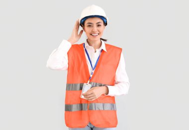 Female worker in vest on light background