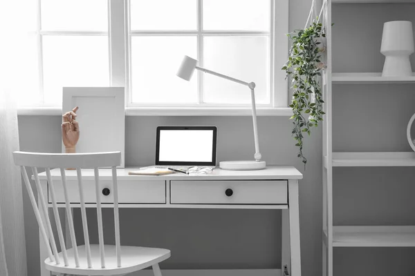 Workplace with laptop in interior of light office