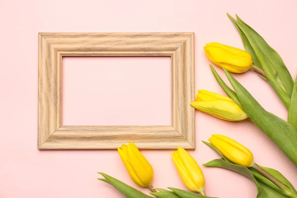 Empty picture frame and yellow tulip flowers on pink background. Hello spring
