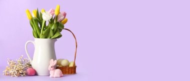 Vase with flowers, Easter eggs and toy bunny on lilac background with space for text