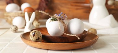 Wooden plates with Easter eggs on table