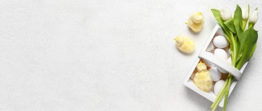 Basket with Easter eggs, chickens and tulip flowers on grey background with space for text