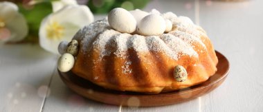 Plate with tasty Easter cake and eggs on white wooden table