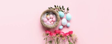 Festive composition with nest of Easter eggs and beautiful flowers on pink background