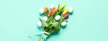 Bouquet of beautiful tulip flowers and Easter eggs on turquoise background