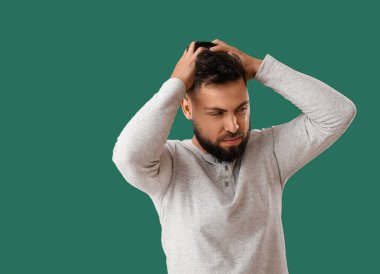 Young man worrying on green background