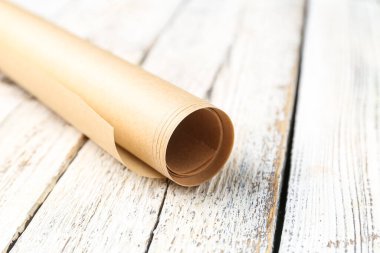 Roll of baking paper on light wooden background, closeup