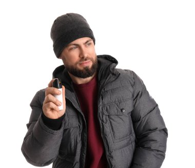 Young man with pepper spray for self-defence on white background