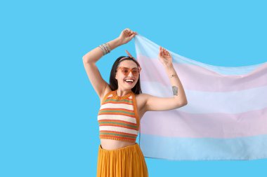 Young woman in sunglasses with transgender flag on blue background