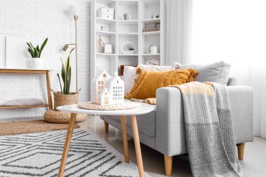 Interior of living room with sofa and glowing house candle holders on table