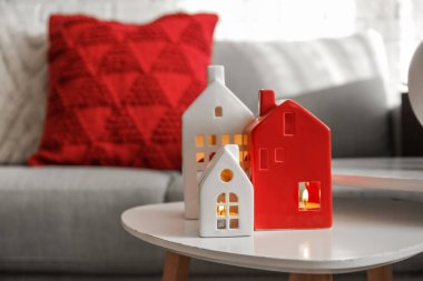 Glowing house candle holders on table in living room