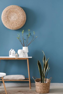 House candle holders, wooden mannequin and houseplant on table near blue wall