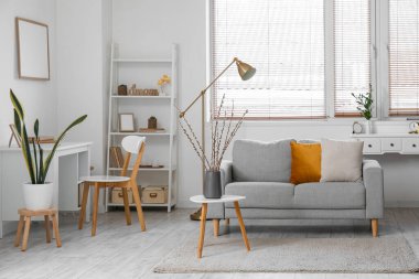 Interior of living room with willow branches in vase and sofa