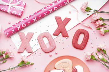 Composition with sweet cookies, wrapping paper and carnation flowers on color background. Valentine's Day celebration