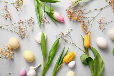 Beautiful composition with flowers and Easter eggs on light background