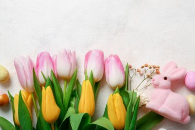 Composition with beautiful flowers, Easter bunny and eggs on light background