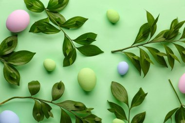 Composition with plant branches and Easter eggs on green background
