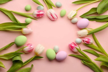 Frame made of beautiful Easter eggs and tulip flowers on pink background
