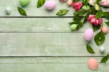 Composition with plant branches, eustoma flowers and painted Easter eggs on color wooden background