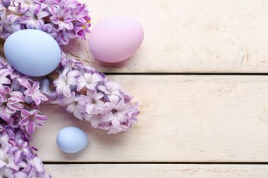 Composition with beautiful hyacinth flowers and painted Easter eggs on light wooden background