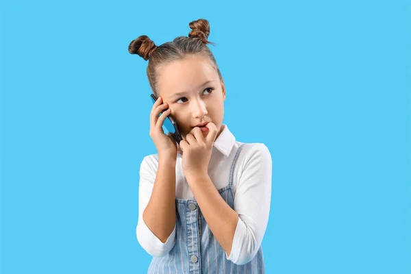 Little Girl Biting Nails While Talking Mobile Phone Blue Background — Stock Photo, Image