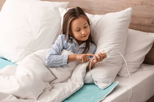 Little girl lying on electric heating pad in bedroom