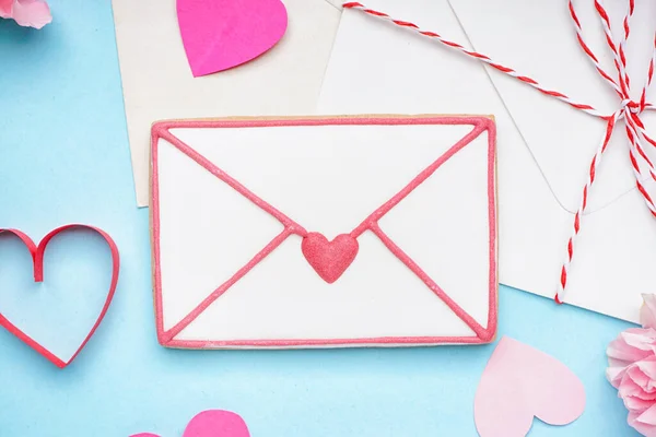 Sweet cookie in shape of letter, envelopes and paper hearts on color background, closeup. Valentine\'s Day celebration