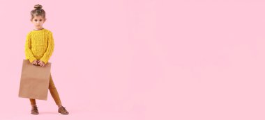 Cute little girl with paper shopping bag on pink background with space for text