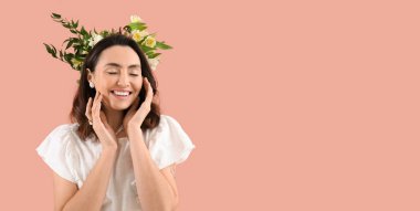 Beautiful happy young woman with flowers on pink background with space for text