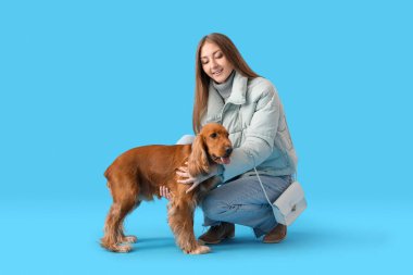 Young woman with red cocker spaniel on blue background