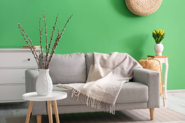Vase with willow branches on table in interior of living room
