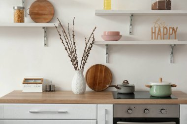 Vase with willow branches on counter in interior of kitchen