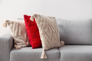 Decorative pillows on sofa near light wall, closeup
