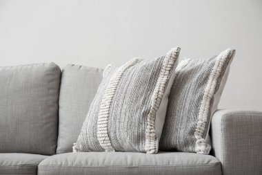 Soft pillows on sofa near light wall, closeup