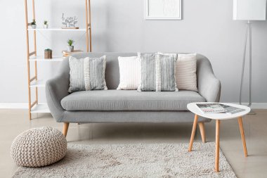 Interior of modern living room with soft pillows on grey sofa