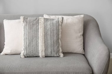 Oturma odasındaki gri koltukta yumuşak yastıklar.