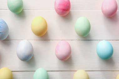 Composition with beautiful Easter eggs on white wooden background