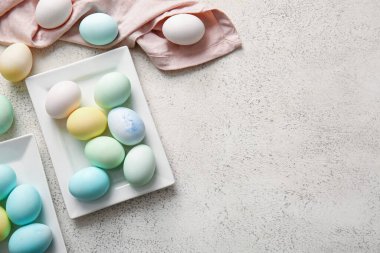 Plates with beautiful Easter eggs on light background