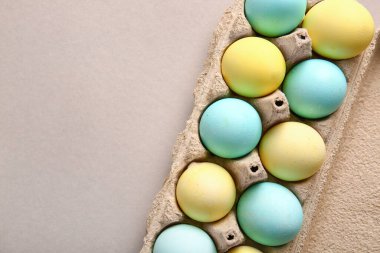 Cardboard holder with painted Easter eggs on grey background, closeup
