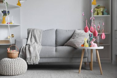 Interior of living room with Easter eggs, tree branches and rabbits